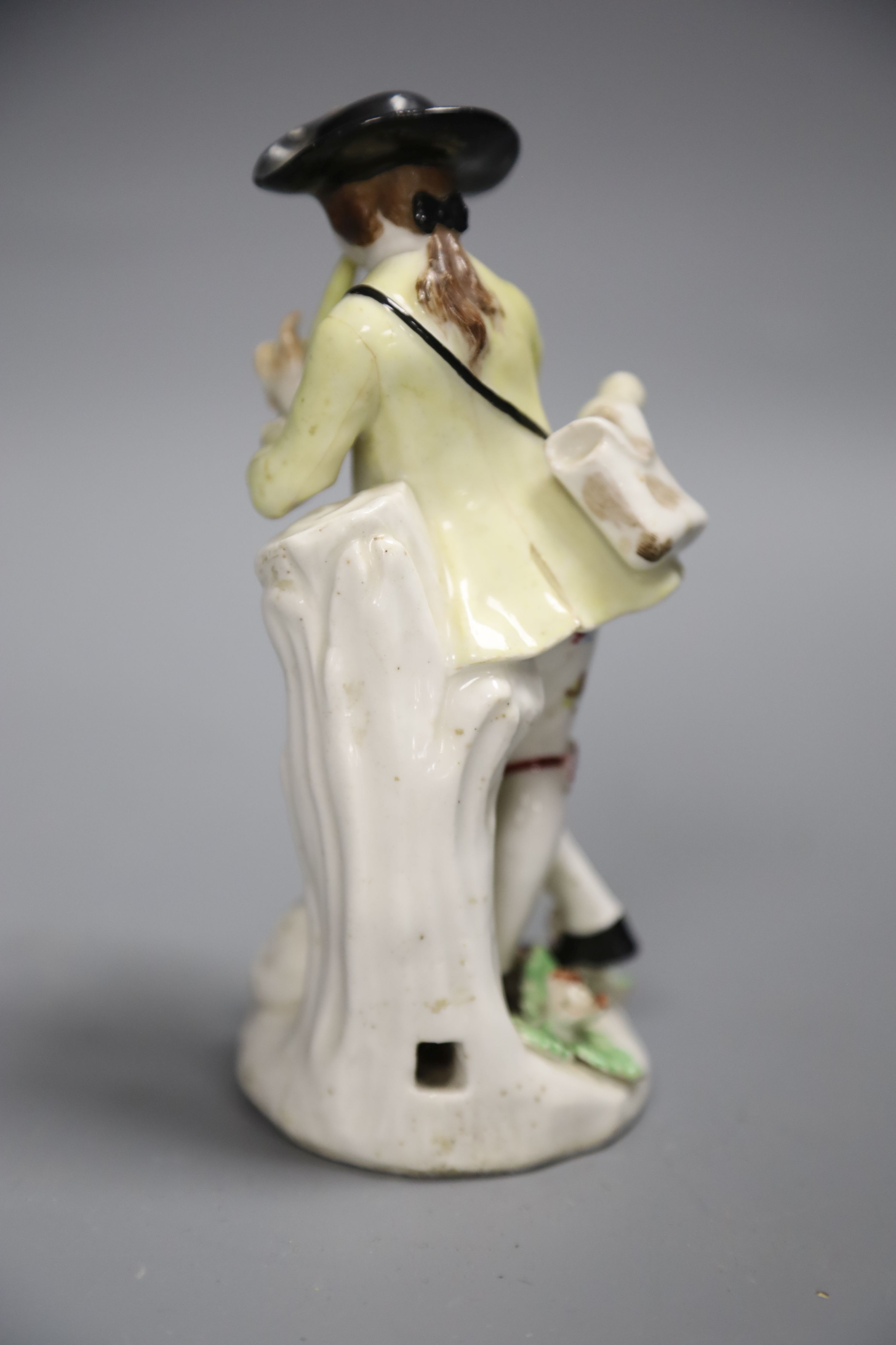 An 18th century Bow figure of a piper with dog after a Meissen model by J.J. Kaendler, height 15cm